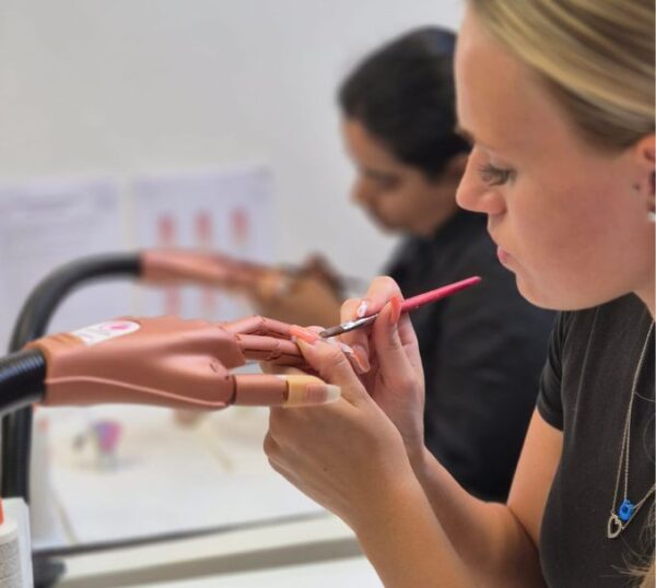 Students practising acrylic nail extensions on practice hands
