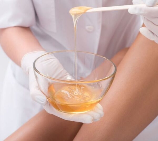 Waxing therapist with a spatula of warm wax