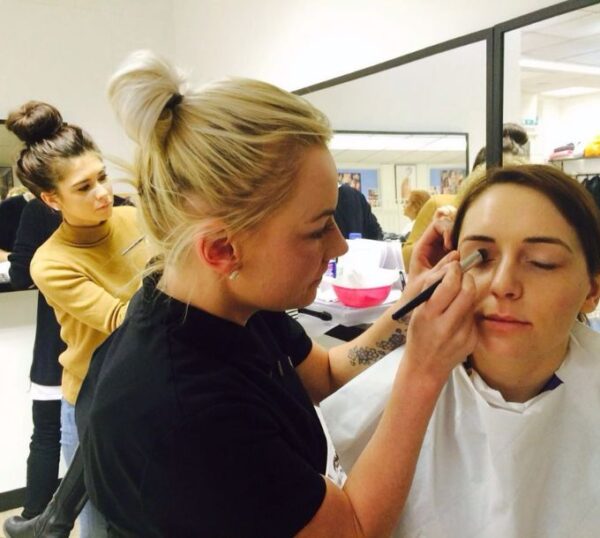 Students practising make-up application in a training class