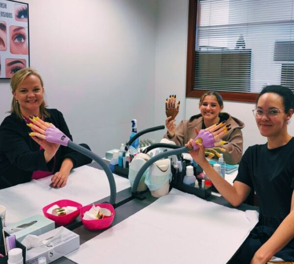 Smiling students showing their nails at a Beauty Academy class