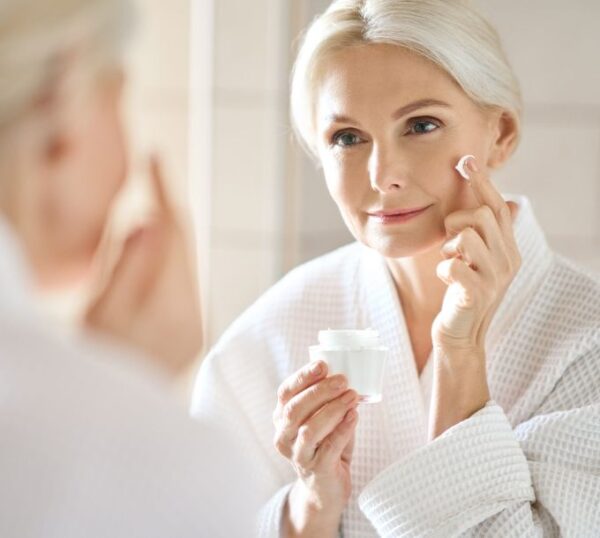 Mature woman applying skincare to her face